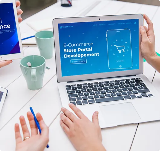 A person working on a laptop that displays an "E-Commerce Store Portal Development" interface with a shopping cart icon.